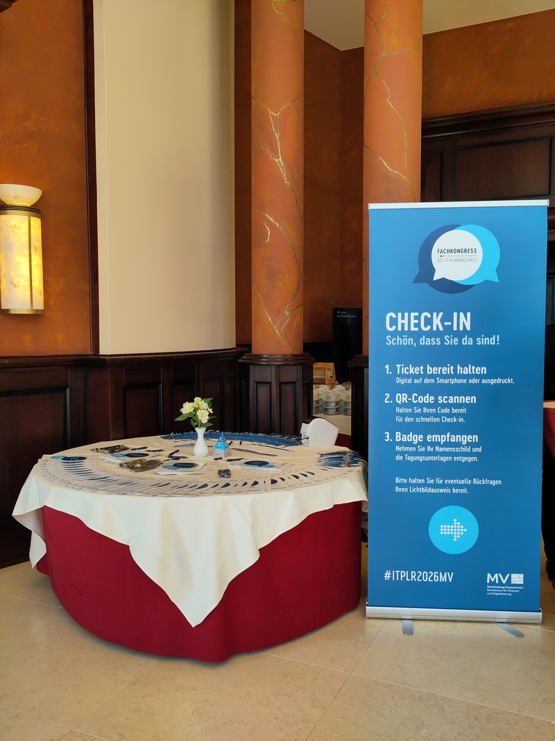Tisch mit Informationen zum Fachkongress und Check-In Aufsteller