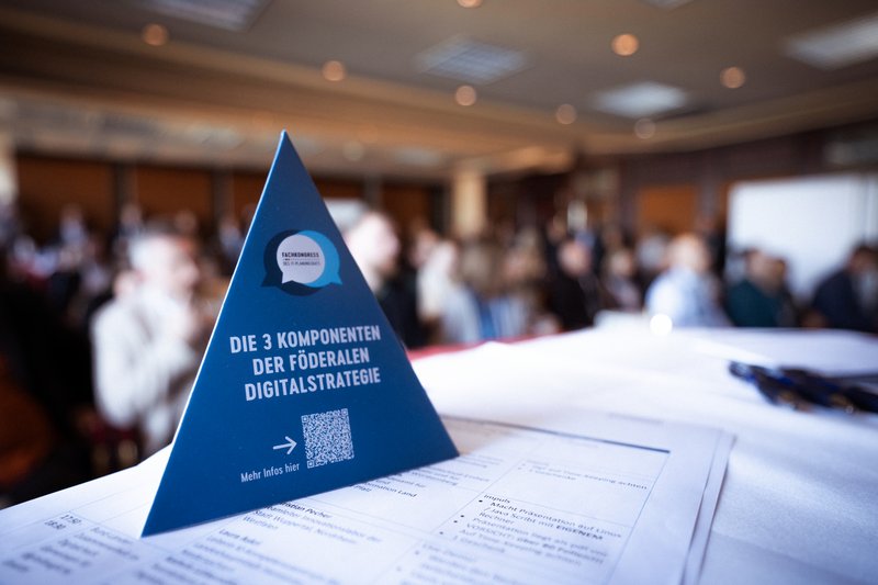 Ein Informationsaufsteller vor Teilnehmern des 14. Fachkongresses